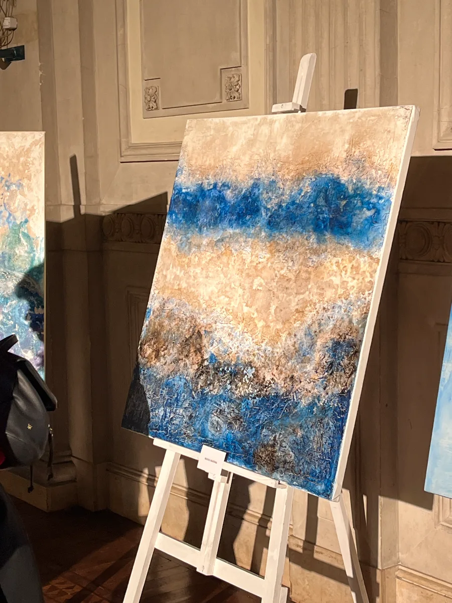 Pintura en azul y ocre sobre un atril en “101 años en colores”