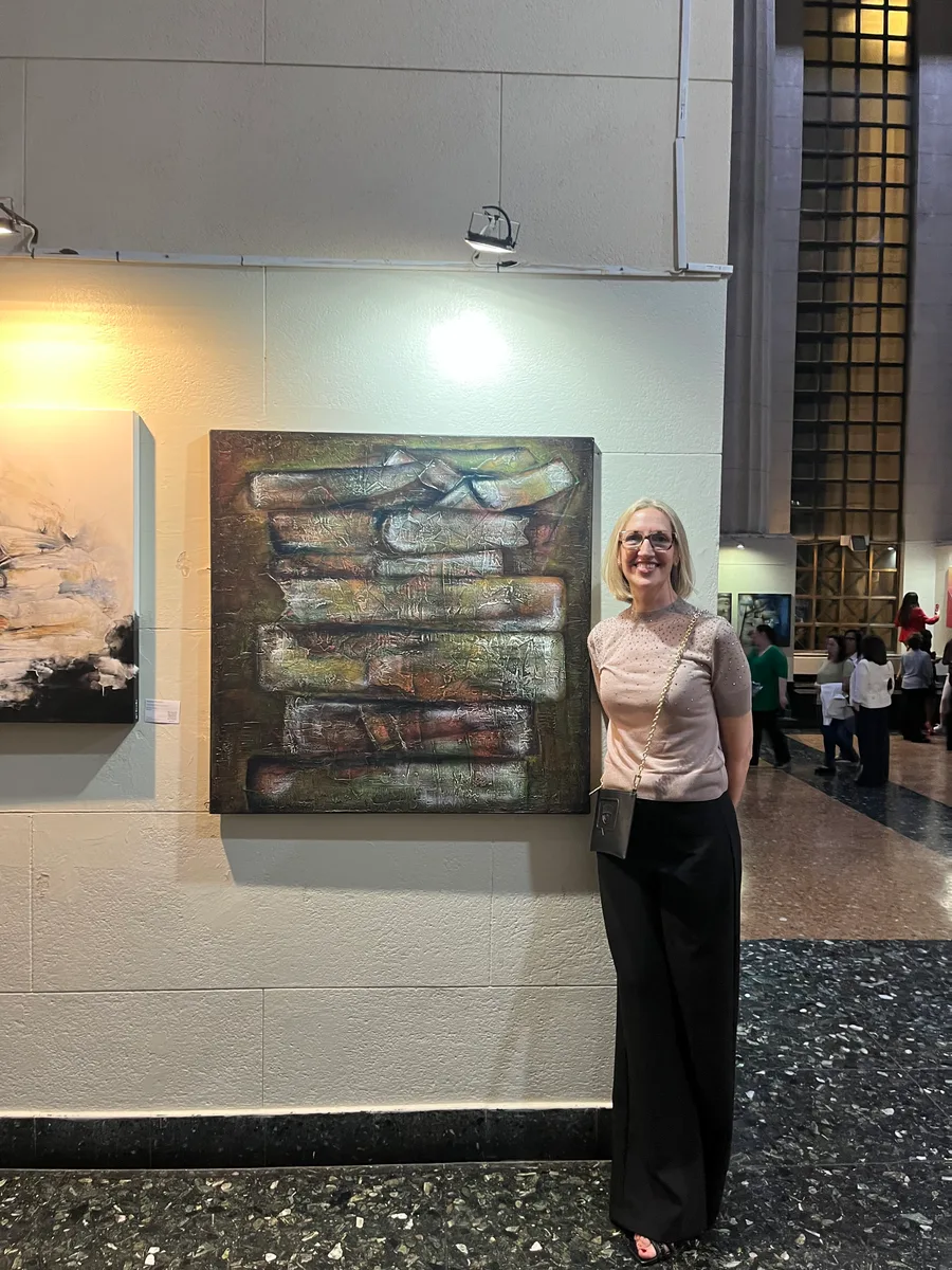 Marina Elizalde junto a una pintura en tonos ocres